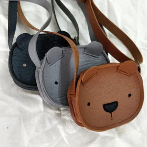 Set of three bear-shaped kids' crossbody bags in black, gray, and brown on white fabric