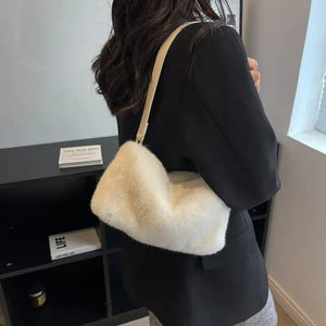 Woman in black blazer carrying a soft white faux fur shoulder bag indoors