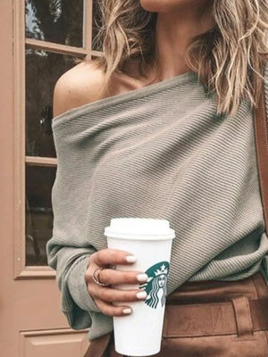 Woman in off-shoulder ribbed sweater holding coffee cup, casual street style fashion