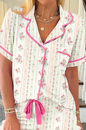 Woman wearing floral striped short-sleeve pajama set with pink trim and waist tie