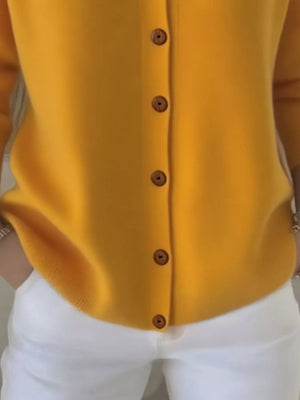 Yellow button-up cardigan paired with white pants, hands in pockets, casual fashion style