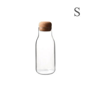 Clear glass bottle with cork lid on white background, minimalist kitchen storage container