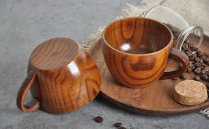 Two wooden coffee mugs on a wooden tray with coffee beans and cork on a grey table