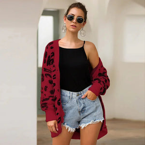 Woman in black tank top, denim shorts, and red leopard print cardigan, wearing sunglasses