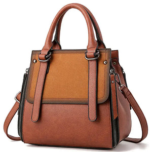 Brown leather tote handbag with top handles, shoulder strap, and zipper accents
