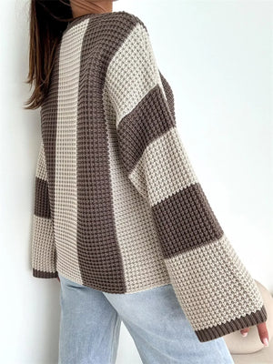 Woman wearing loose knit sweater with beige and brown stripes and light wash jeans