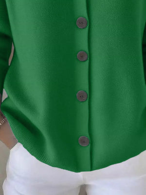 Green button-up cardigan with black buttons paired with white pants
