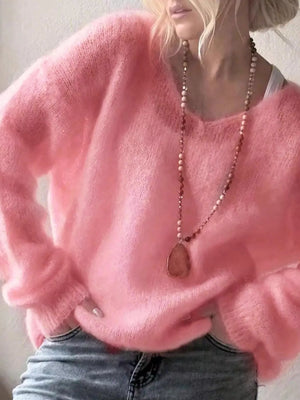Woman in soft pink fuzzy sweater, long beaded necklace, and blue jeans