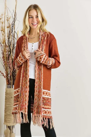 Woman wearing a long rust orange knit cardigan with fringe and ethnic patterns, casual outfit