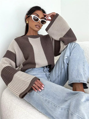 Woman in striped knit sweater and light blue jeans, wearing white cat-eye sunglasses