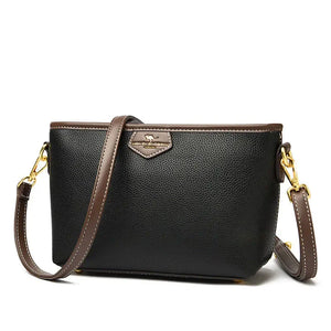 Black textured leather crossbody bag with brown trim and gold hardware