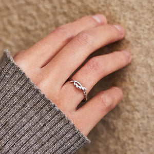 Delicate silver leaf design ring on hand wearing a ribbed sweater