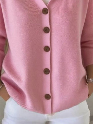 Pink button-up cardigan with brown buttons, worn with white pants, casual women’s fashion