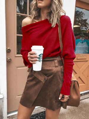 Woman in a red off-shoulder sweater and brown suede mini skirt holding a coffee cup