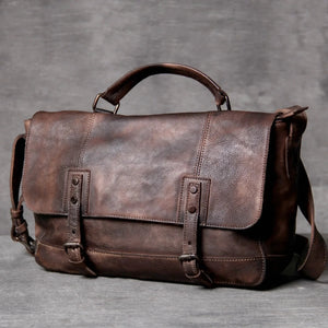Brown leather messenger bag with adjustable strap and buckle closures on a gray background