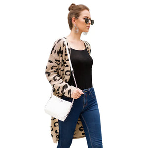 Woman in leopard print cardigan, black top, blue jeans, white shoulder bag, sunglasses