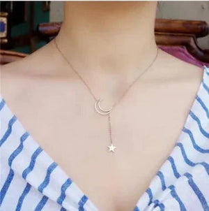 Delicate moon and star pendant necklace worn with a striped V-neck dress, minimalist jewelry