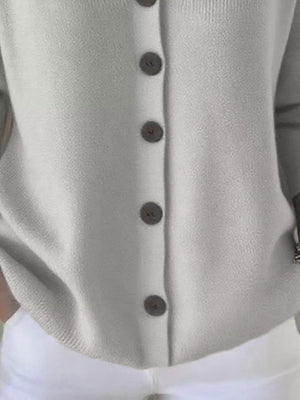 Light grey button-front knit cardigan paired with white pants, casual fashion style
