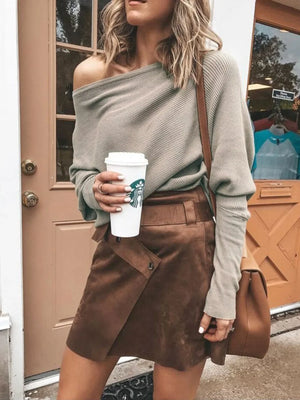 Woman wearing off-shoulder ribbed sweater and brown suede mini skirt holding coffee