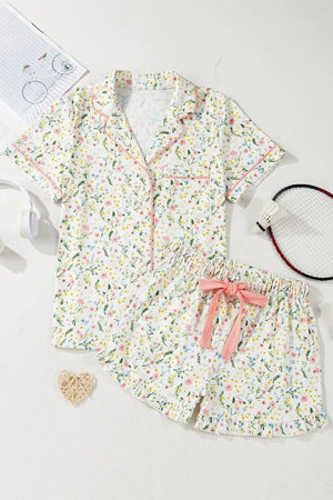Floral print short sleeve pajama set with pink trim and bow, laid flat on white background
