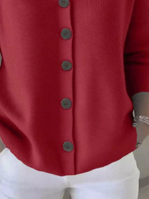 Red button-up cardigan with black buttons, paired with white pants