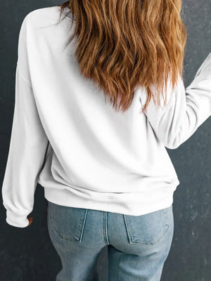 Woman wearing a white sweatshirt and blue jeans, shown from the back against a dark wall.