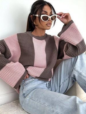 Woman wearing pink and brown striped knit sweater, light blue jeans, and white cat-eye sunglasses