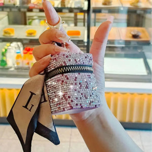 Hand holding a sparkly rhinestone keychain pouch with zipper, attached scarf accent.