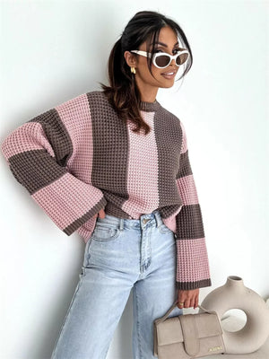 Woman wearing pink and brown striped knit sweater, light blue jeans, white sunglasses, holding beige handbag