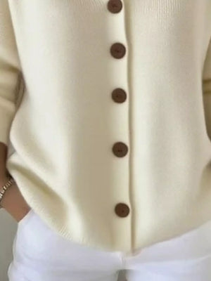 Cream knit cardigan with brown buttons, paired with white pants, casual fashion style