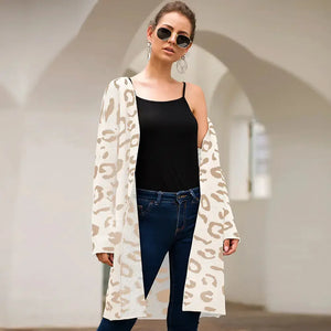 Woman wearing beige leopard print cardigan over black top and jeans, standing outdoors