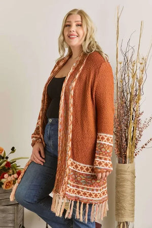 Woman wearing a rust orange boho knit cardigan with fringe and patterned trim, casual style