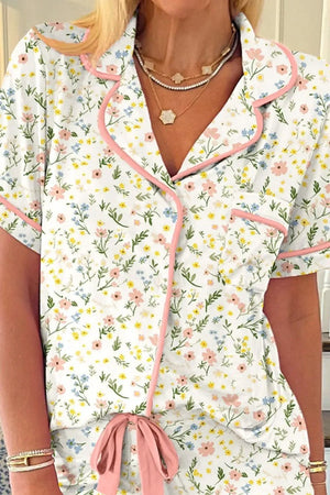 Woman wearing floral print pajama set with pink trim and short sleeves