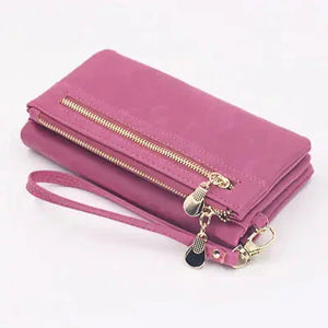 Pink women’s wallet with gold zipper, wrist strap, and decorative charm, on white background