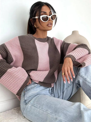 Woman wearing oversized pink and brown knit sweater, light wash jeans, and white sunglasses