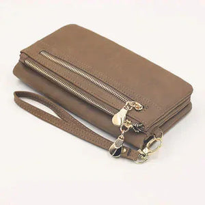 Brown leather wallet with wrist strap and gold zipper details on white background
