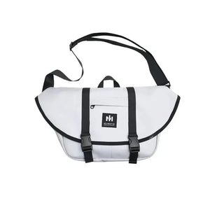 White messenger bag with black trim and adjustable shoulder strap, front buckles visible