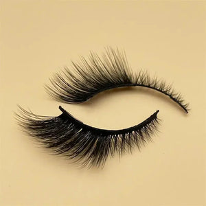 Pair of dramatic black false eyelashes on beige background
