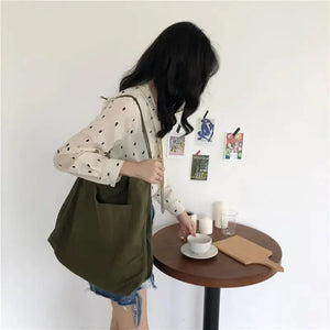 Woman with an olive green tote bag, polka dot blouse, and denim skirt at a round table