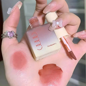 Hand holding pink DAIMANPU liquid lipstick with swatches on palm, showing glossy finish.