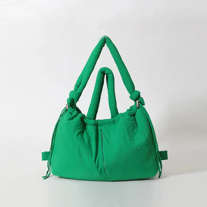 Stylish green puffer tote bag with knotted handles, fashion accessory on plain background