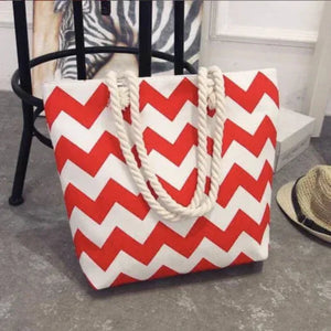 Red and white chevron striped tote bag with rope handles on a gray floor