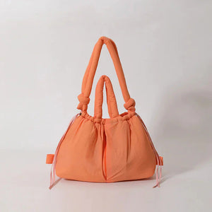 Peach orange puffy tote bag with knotted handles and soft ruched design on white background