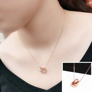 Rose gold interlocking ring pendant necklace on model, minimalist jewelry close-up