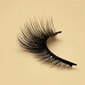 Single dramatic false eyelash with thick, wispy black lashes on a neutral background