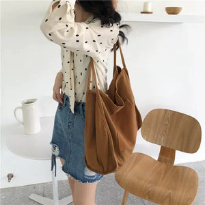 Woman in polka dot blouse and denim skirt carrying a brown tote bag in a modern room