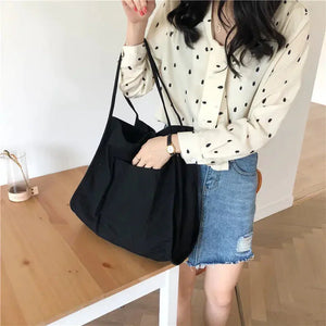 Woman wearing polka dot blouse and denim skirt holding black tote bag