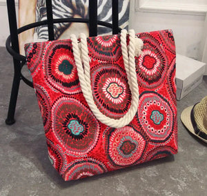 Colorful red patterned tote bag with thick rope handles on a gray floor