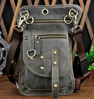 Vintage brown leather crossbody bag with brass studs and zippers on wooden background