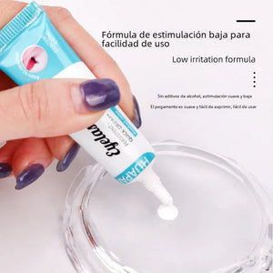 Hand squeezing low irritation eyelash adhesive onto a clear dish, close-up.